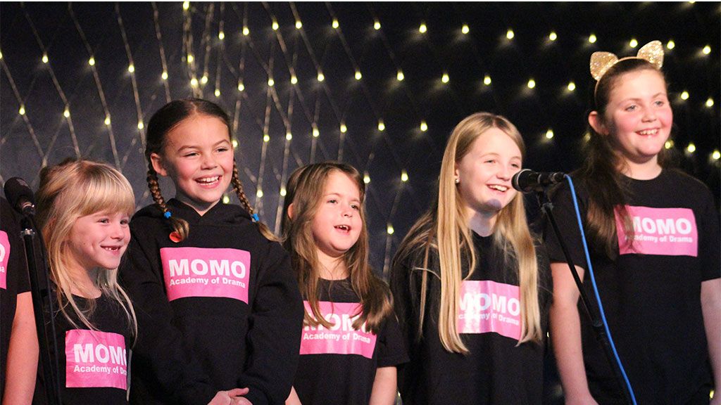 MOMO Academy of Drama group girls performing in front of microphone